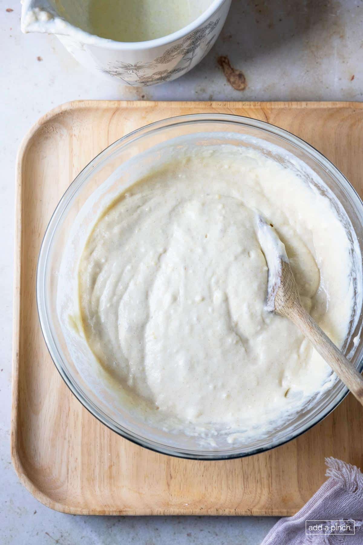 Buttermilk pancake batter in a glass bowl with a wooden spoon. 