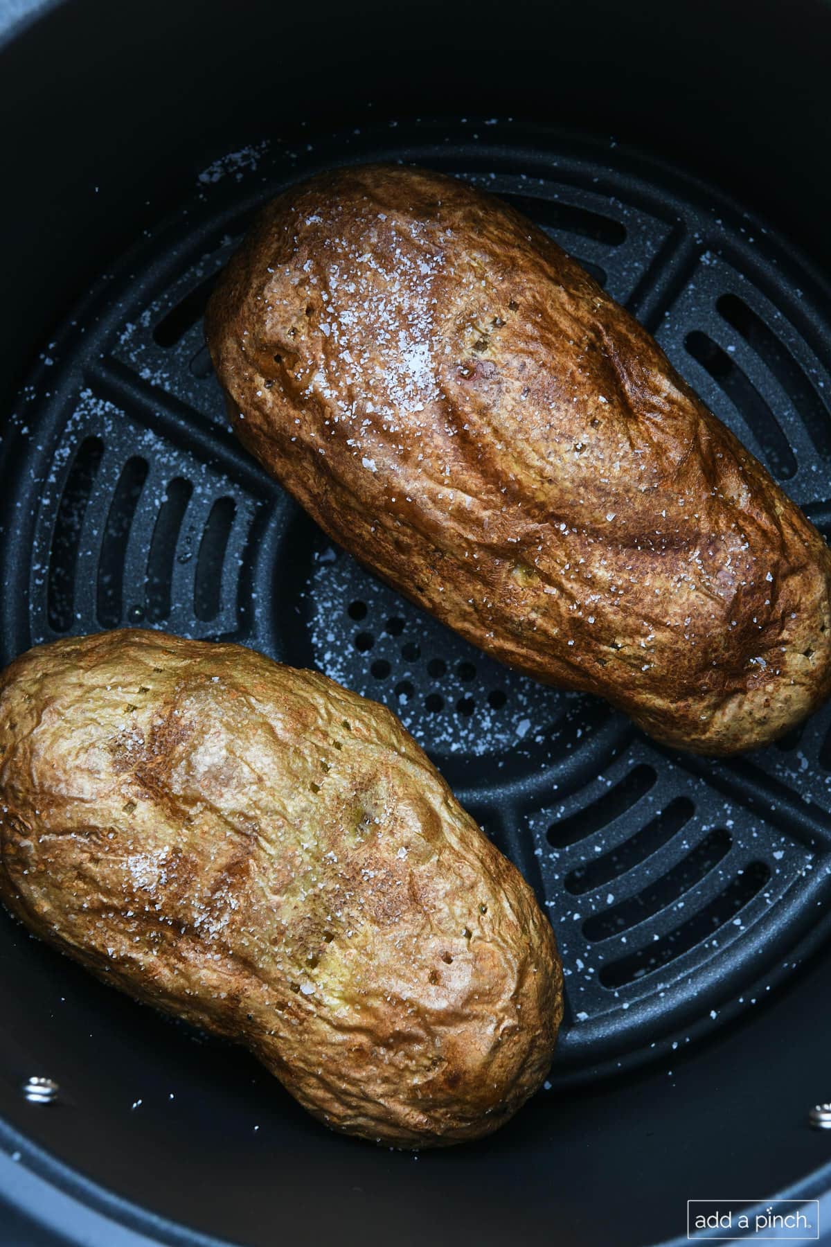 Baked potatoes in an air fryer basket.