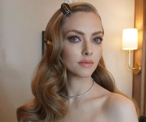 Amanda Seyfried as Elizabeth Holmes in "The Dropout," with styled hair and makeup, wearing a strapless outfit.