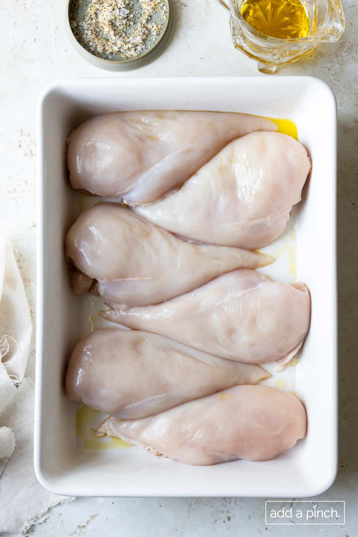Ingredients used to make the best baked chicken recipe - fresh boneless skinless chicken breasts, olive oil, and Stone House Seasoning. 