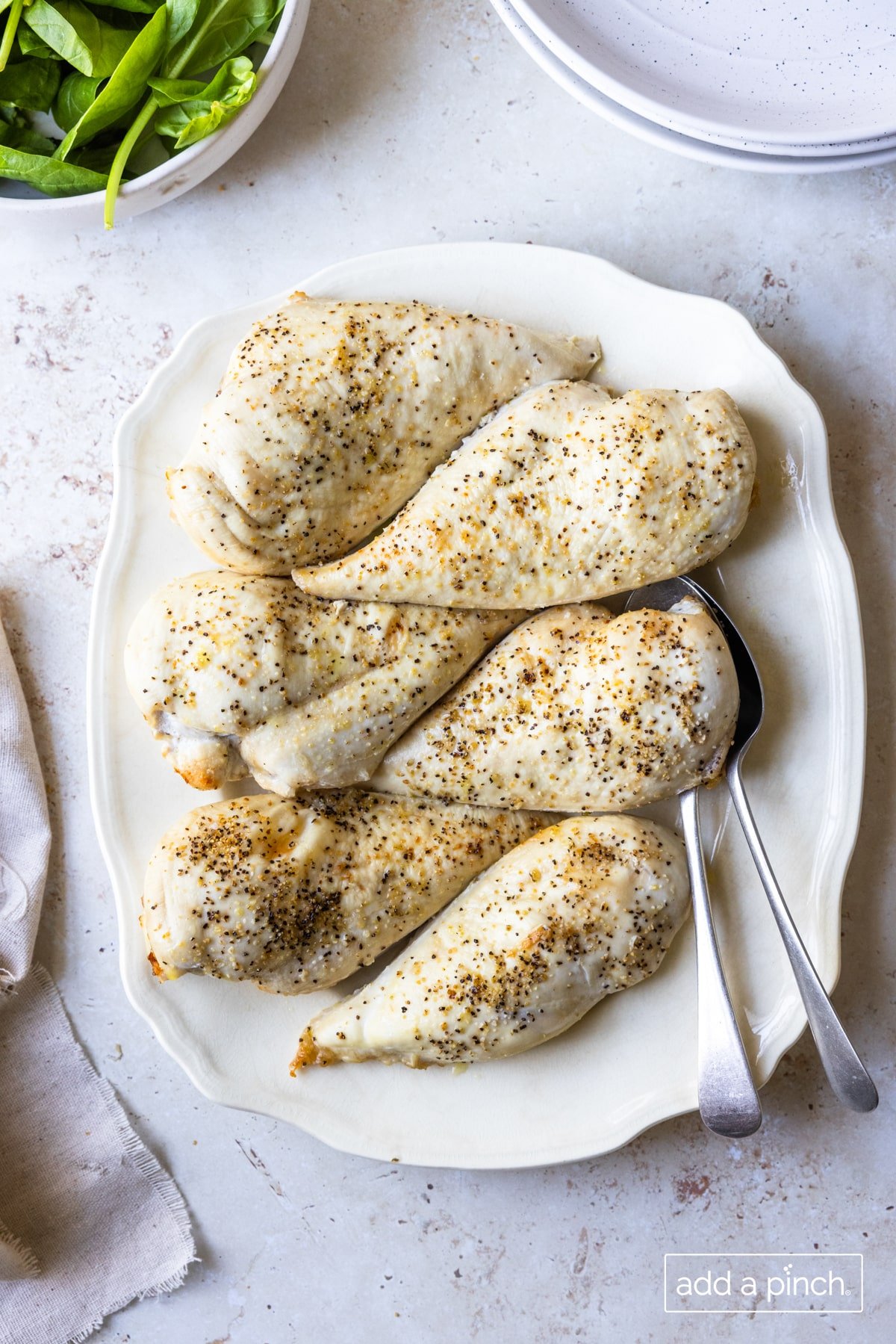 Photo of seasoned baked chicken breasts on a white platter.