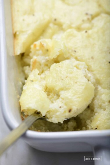 Photo of baked grits casserole in a baking dish on a marble surface.