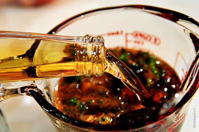 Beer being poured into a glass measuring cup with marinade ingredients// addapinch.com