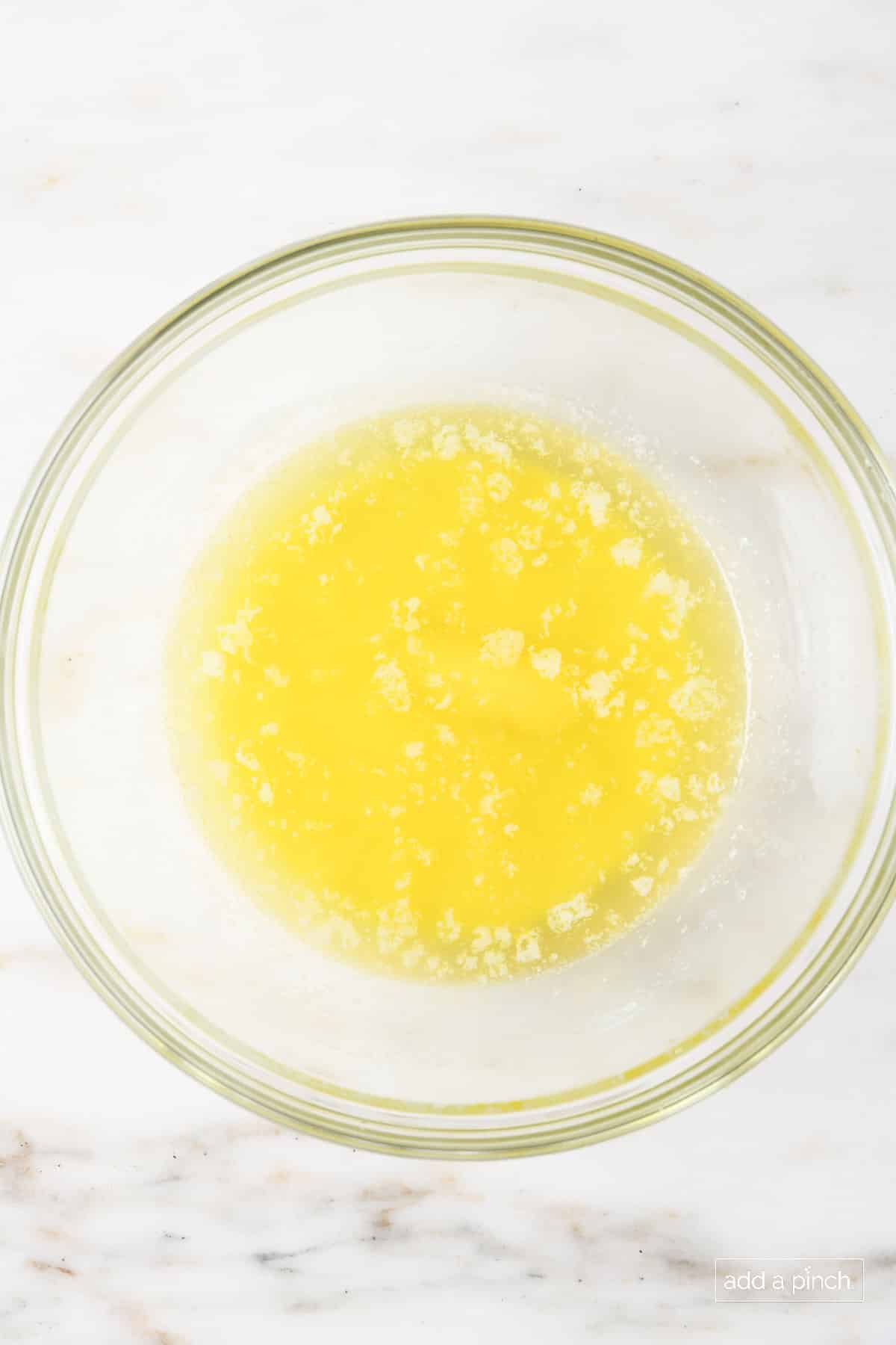 Glass bowl with melted butter on a marble counter. 