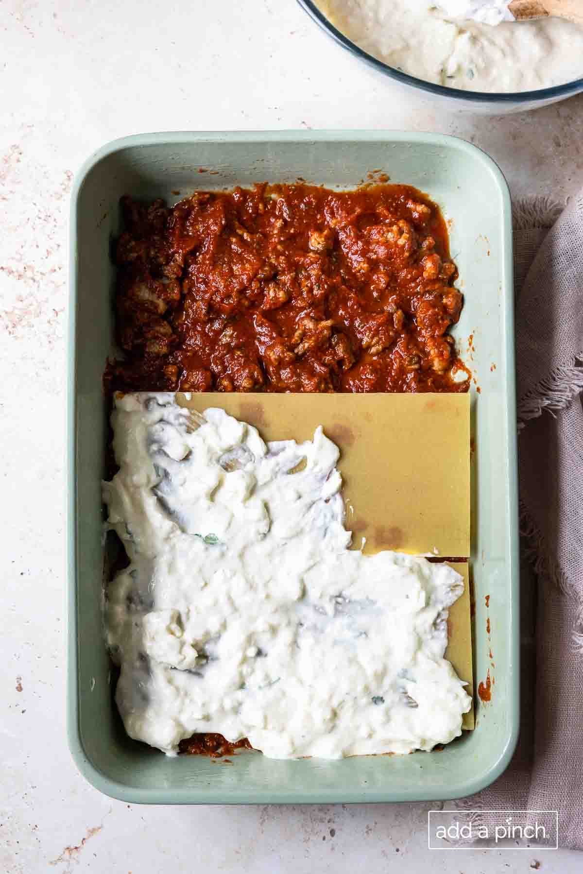 Image of lasagna recipe layers in a 9x13 baking dish. Layers of meat sauce, al dente noodles, and cheese filling.