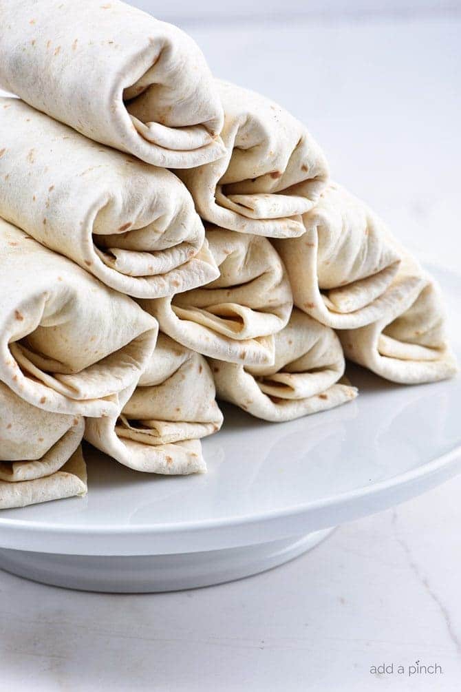 Breakfast burritos on a white plate ready to be served or prepped to freeze.