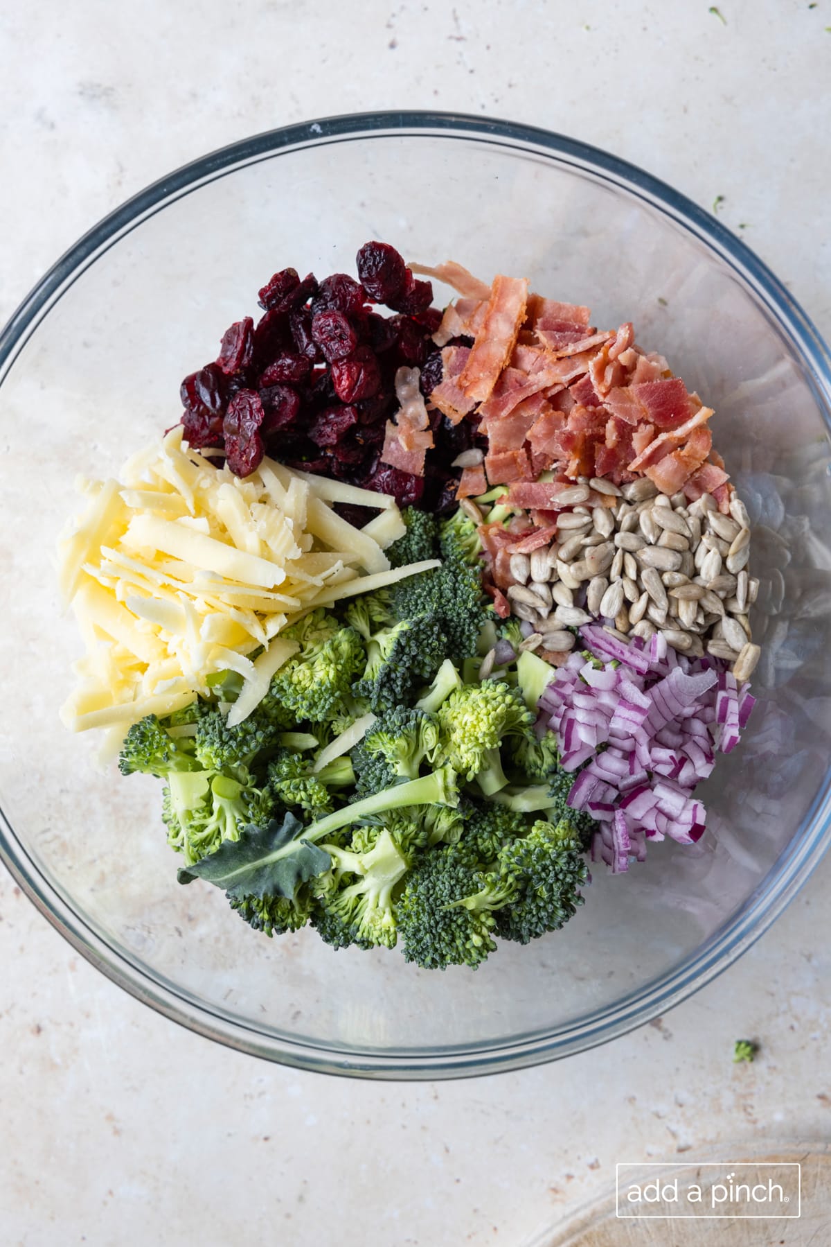 Broccoli salad recipe ingredients in a glass bowl ready for the dressing.