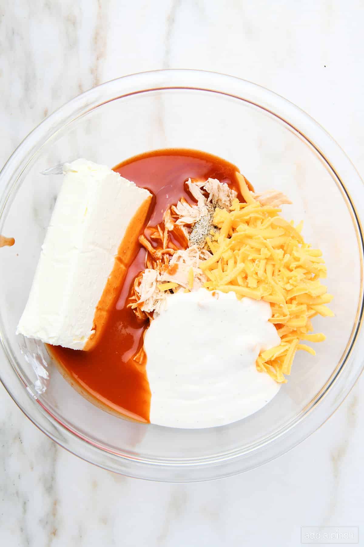 Ingredients for buffalo dip in a glass mixing bowl.