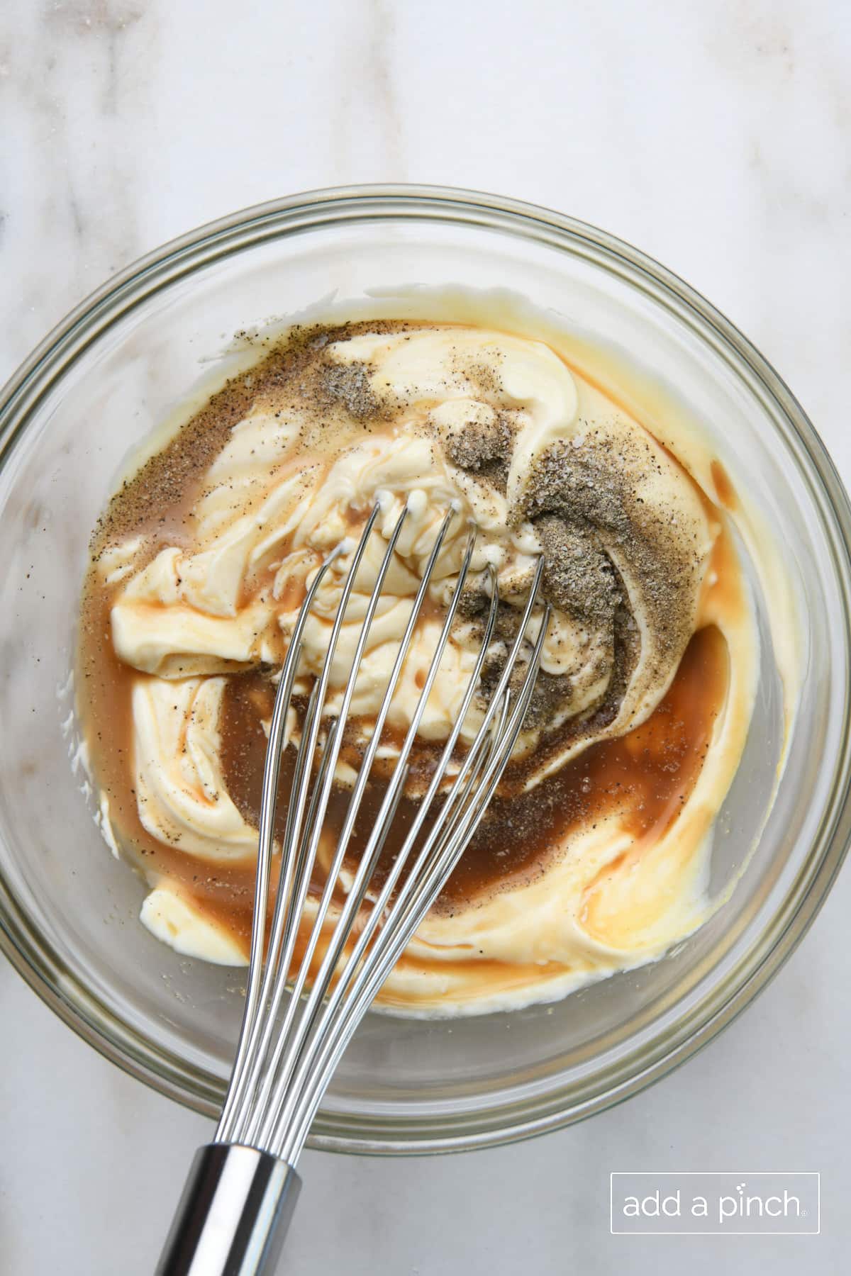 Caesar dressing ingredients in a mixing bowl with a whisk.