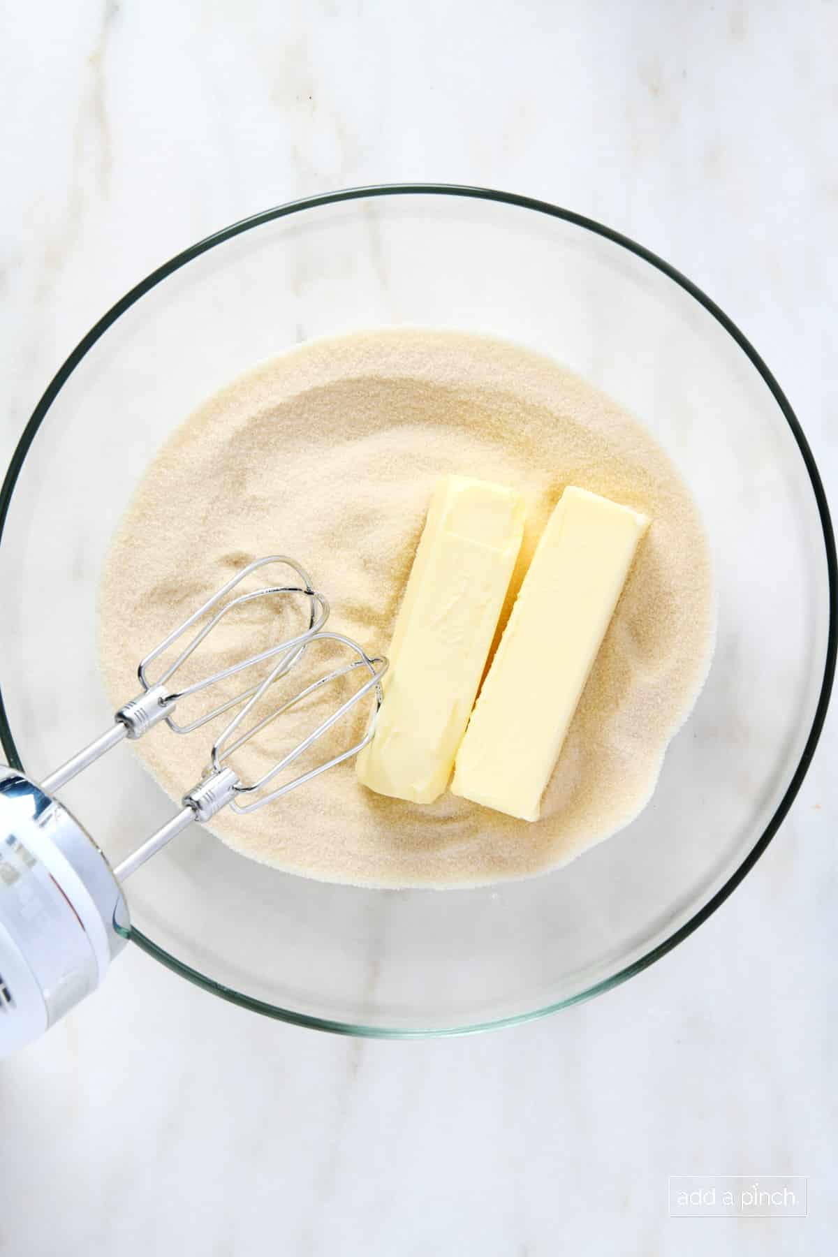 Butter and sugar in a glass mixing bowl with electric hand mixer.