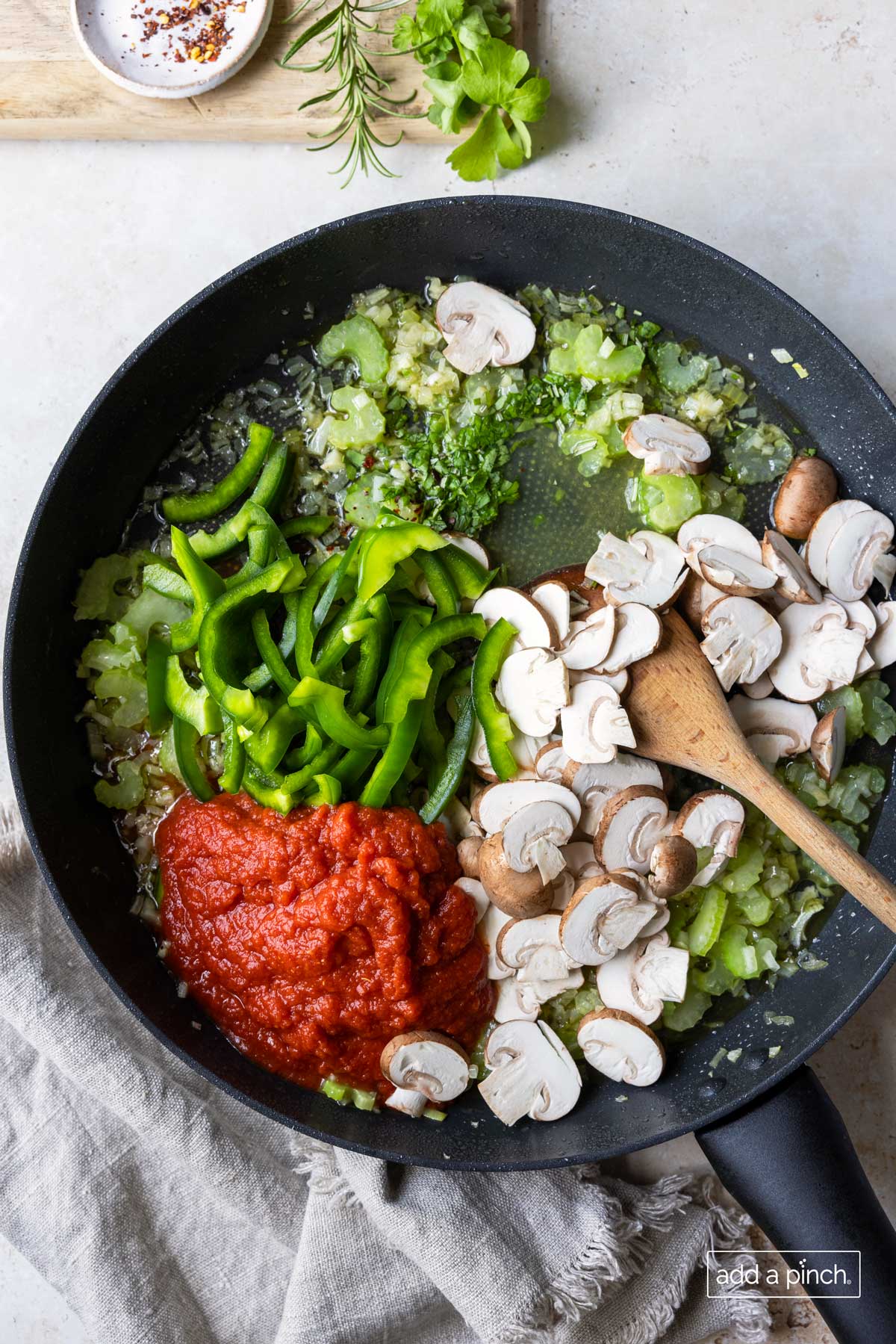 Vegetables, herbs, chicken stock and crushed tomatoes all cooking in a skillet.