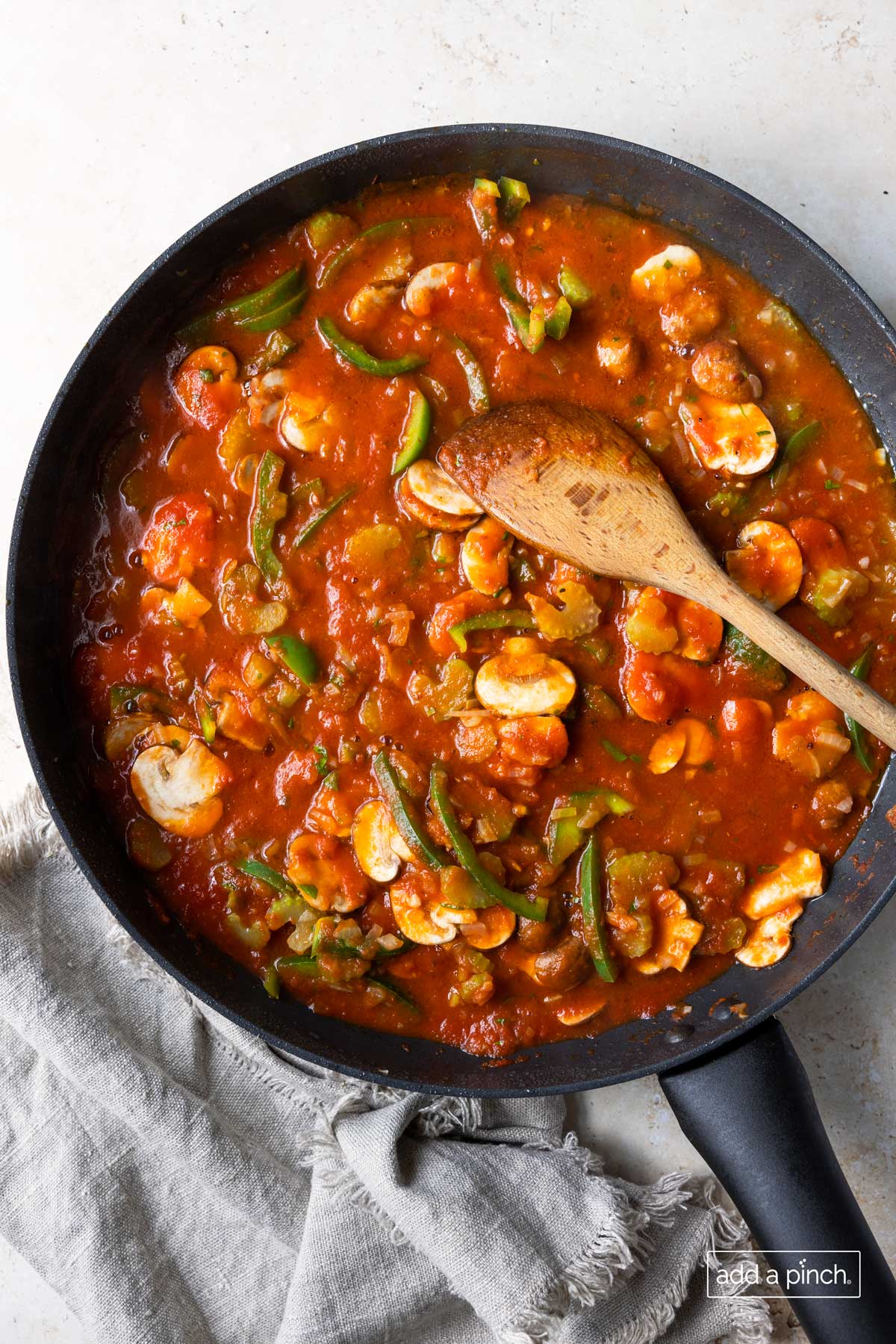 Simmering vegetables and herbs in tomato sauce in a skillet.