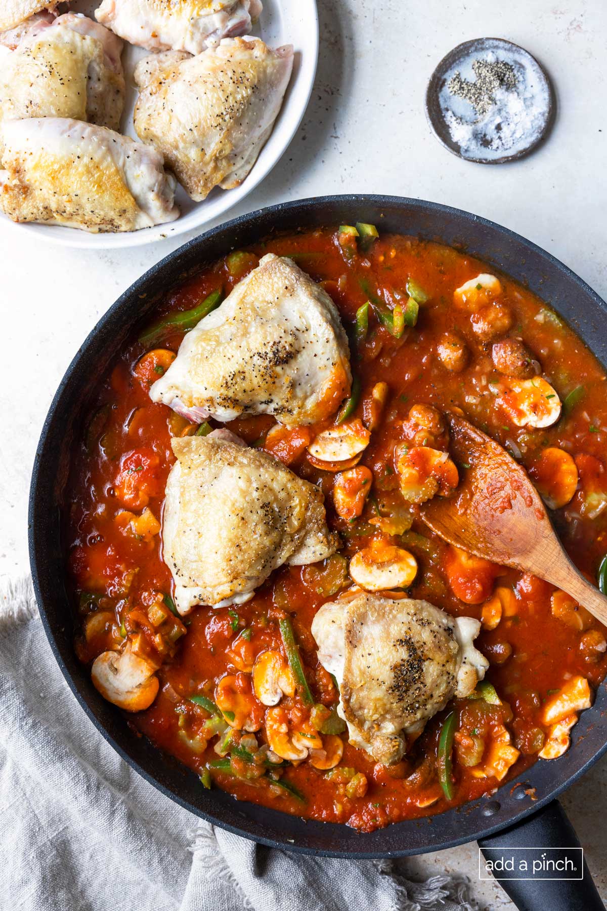 Chicken added back to reduced chicken cacciatore sauce in a skillet.