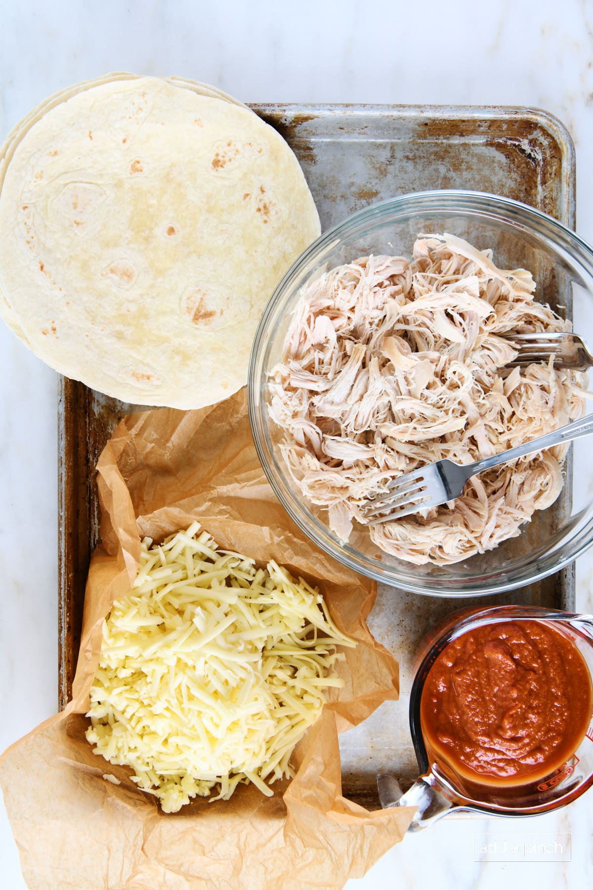 Ingredients to make chicken enchiladas on a baking sheet.