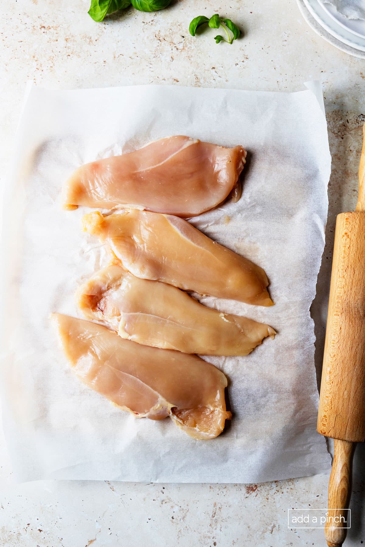 Overhead photo of chicken breasts that have been pounded with a rolling pin until they are thin.