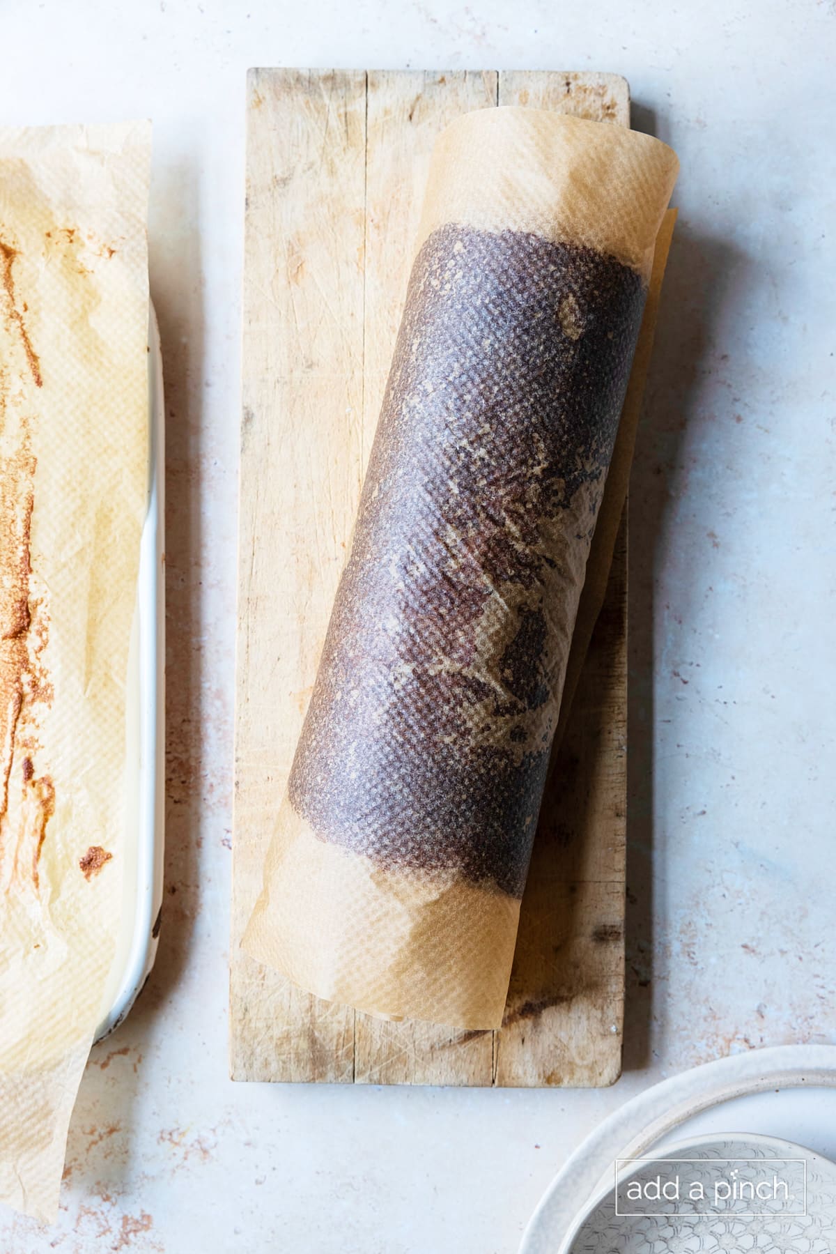 Baked chocolate cake sponge rolled in parchment to cool completely.