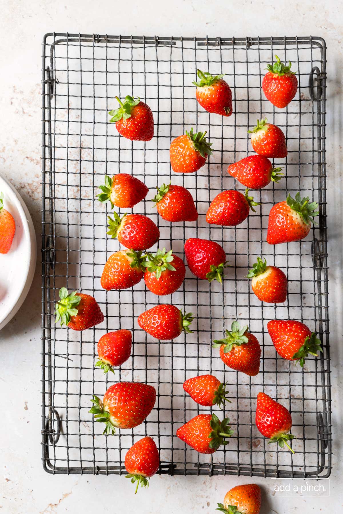 Clean strawberries drying on a wire rack.