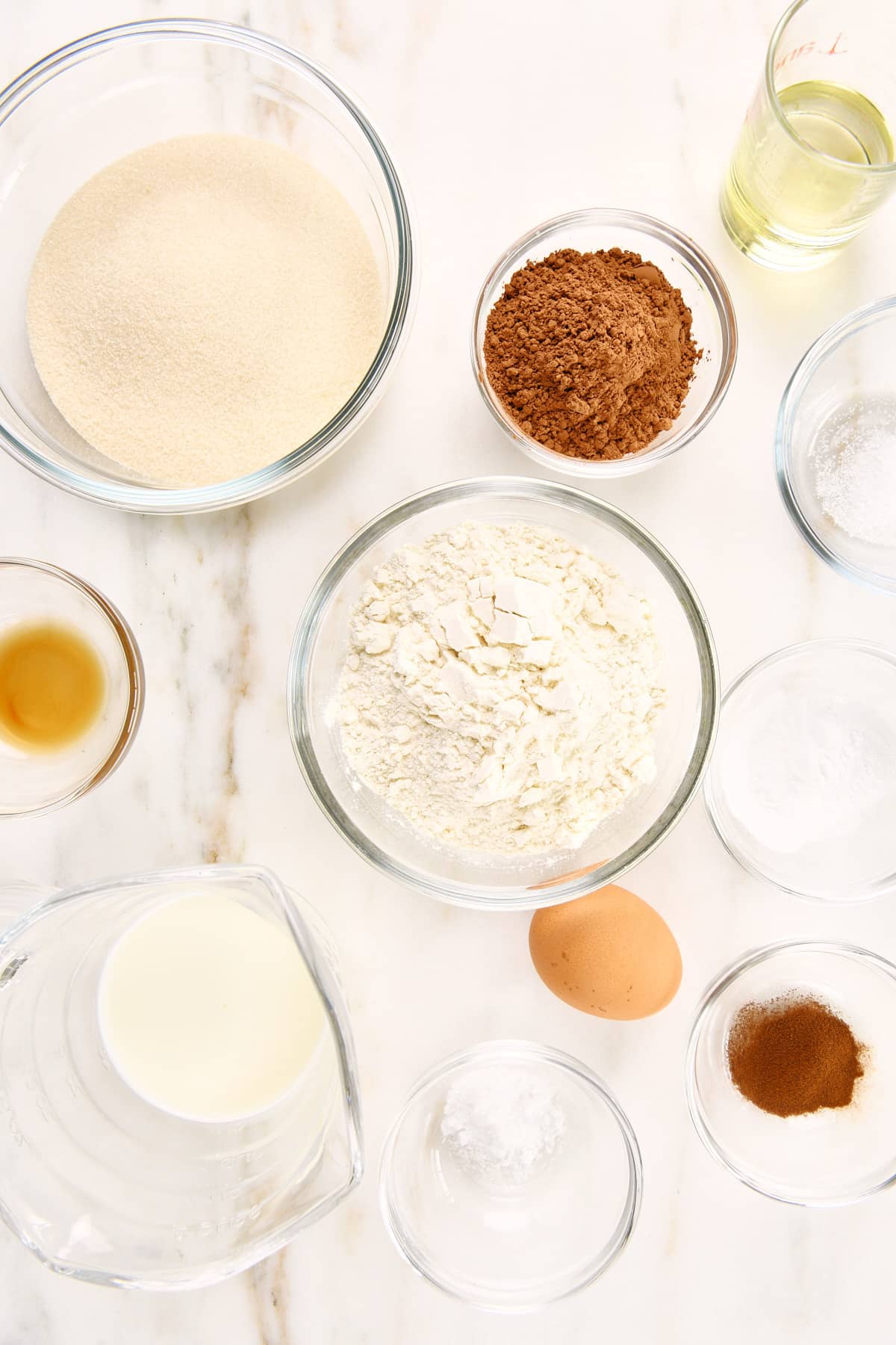 Ingredients used to make chocolate loaf cake recipe on a marble surface.