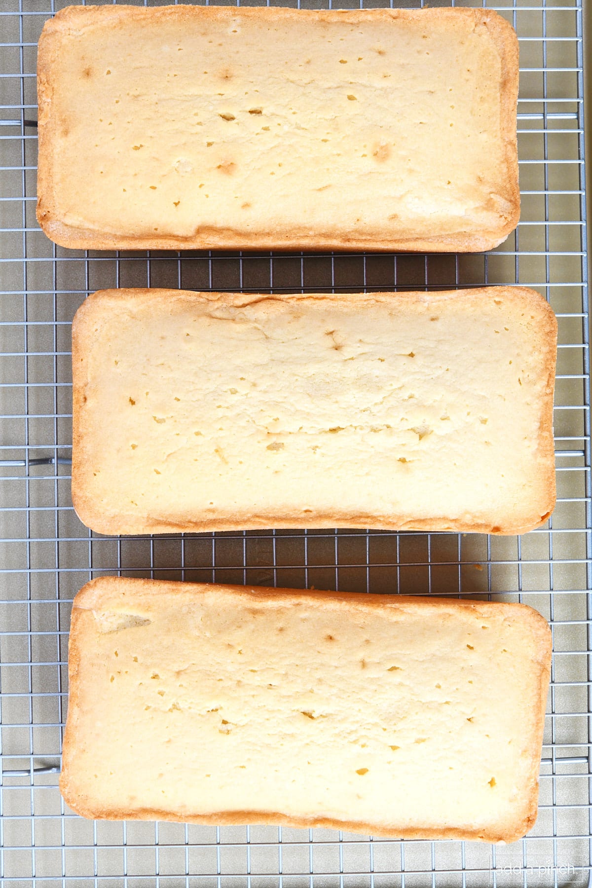 Three golden brown pound cakes cool on a wire rack. 