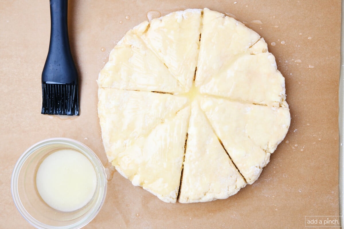 Scones dough on a parchment paper brushed with butter.