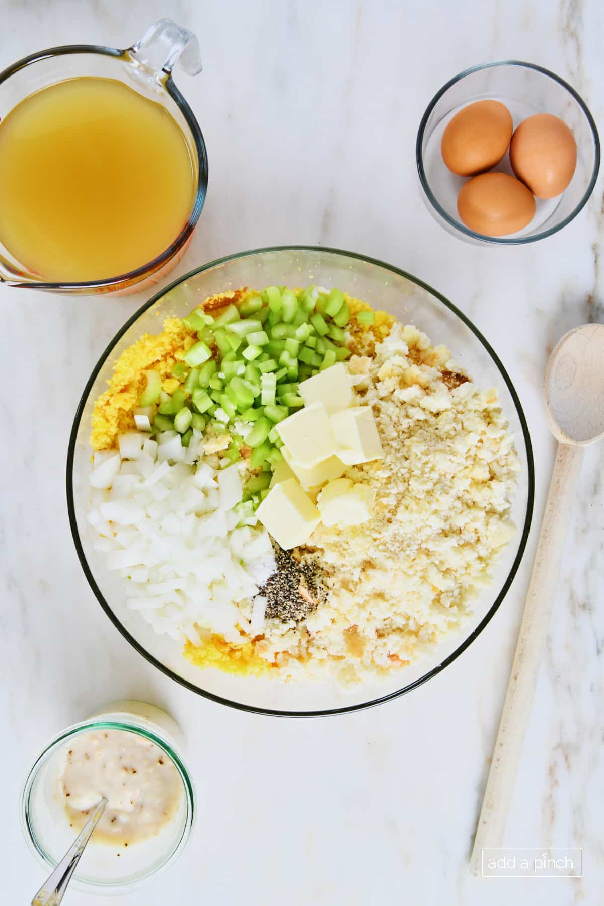 Crumbled cornbread and biscuits in a glass bowl with celery, onion, butter, salt and pepper.