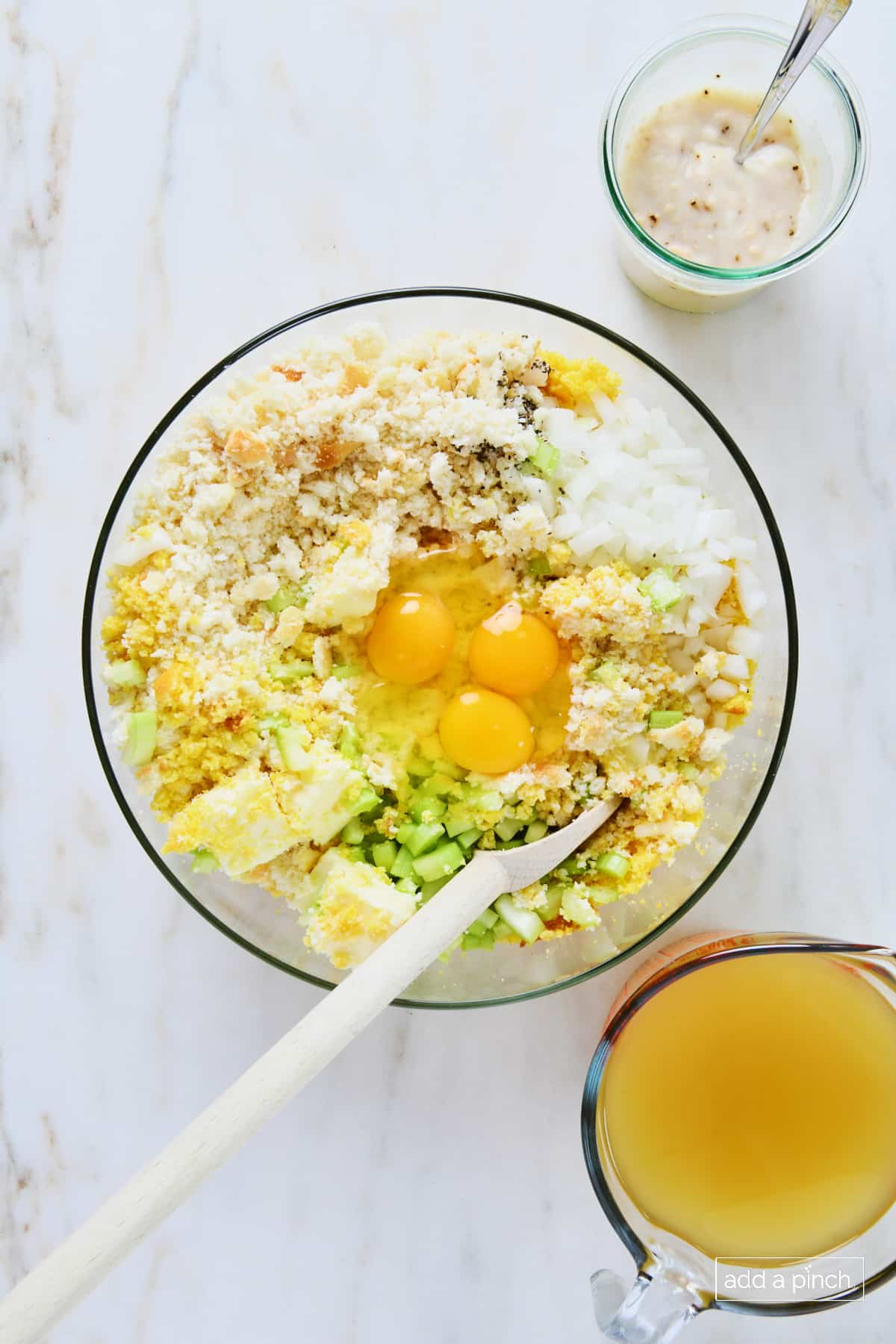 Eggs added to a glass bowl of other cornbread dressing ingredients.