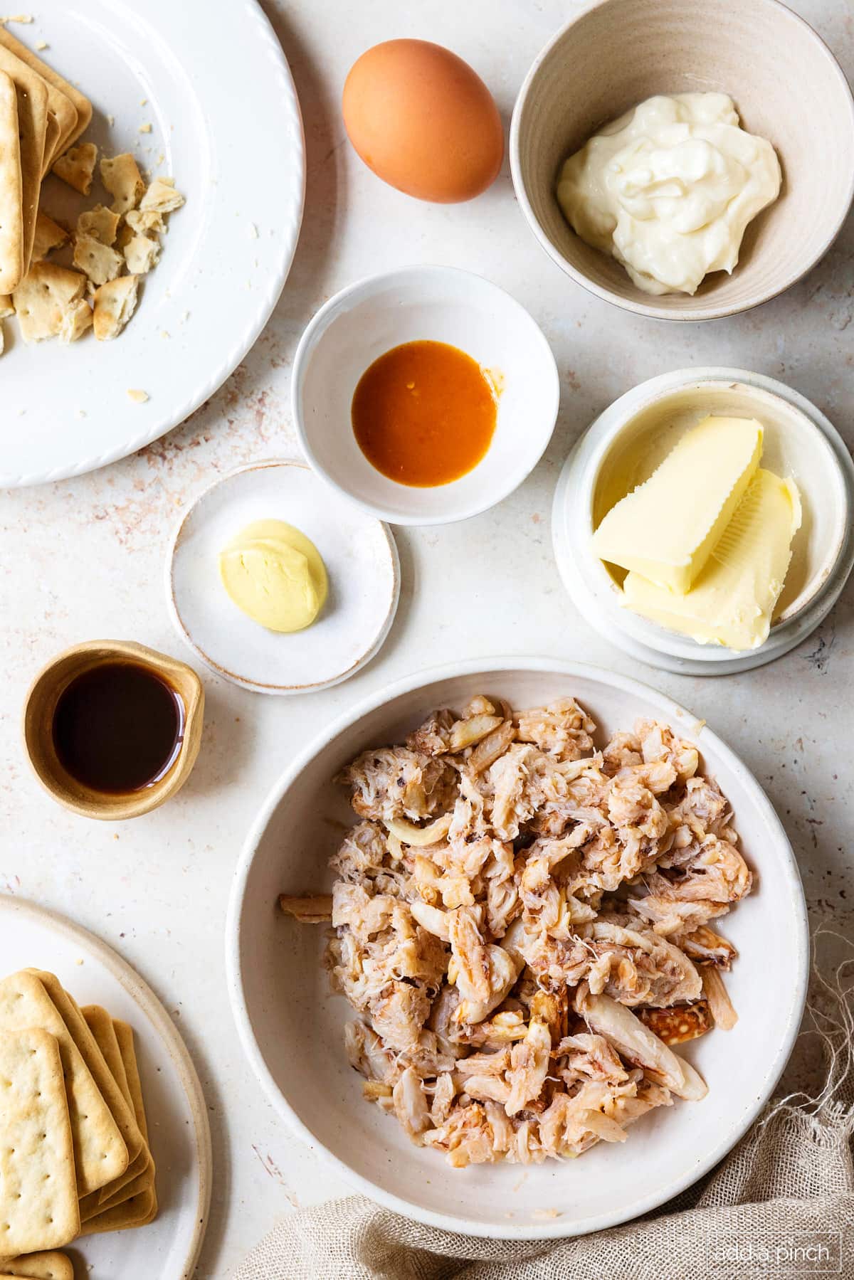 Ingredients for crab cakes: lump crab, butter, hot sauce, mustard, mayo, Worcestershire sauce and saltines in bowls. 