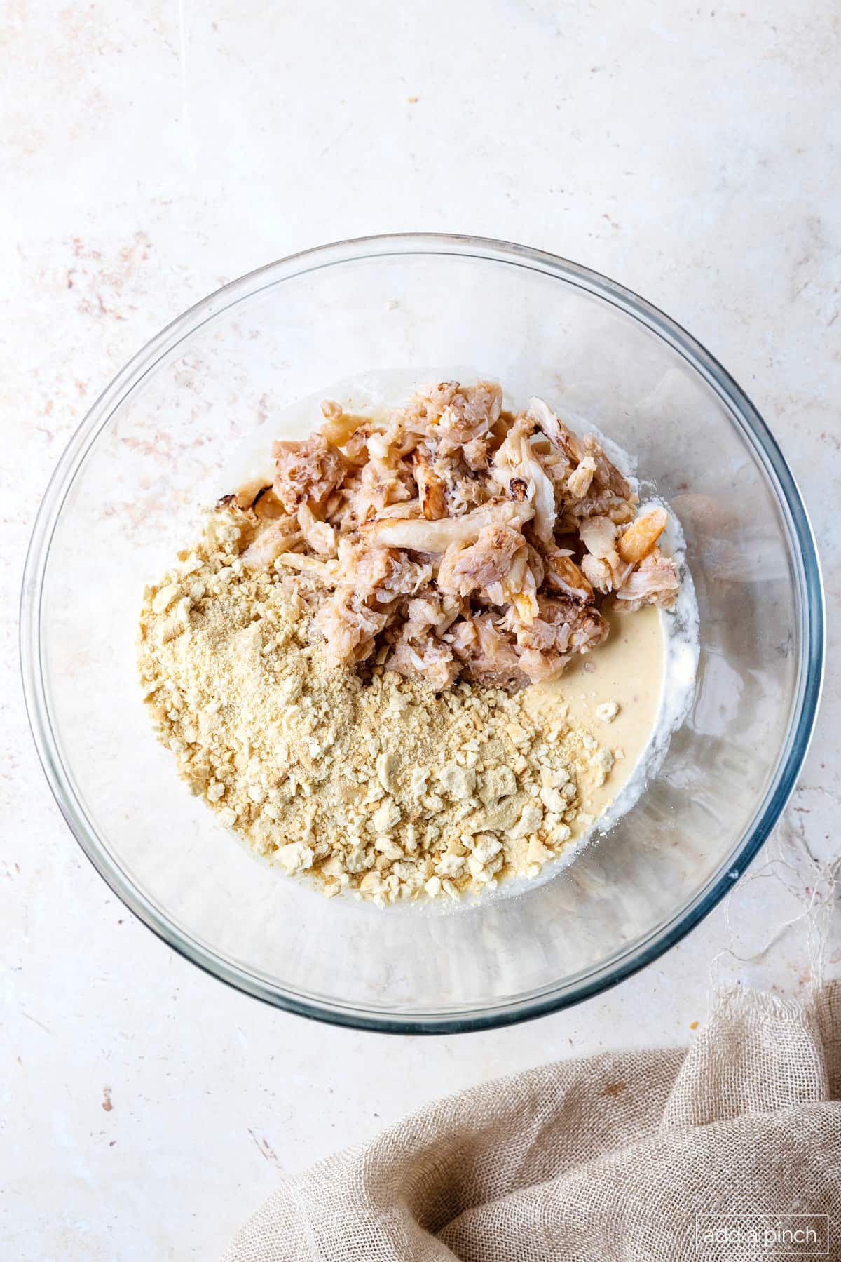 Glass bowl with mayo mixture and lump crab meat and crushed saltines.