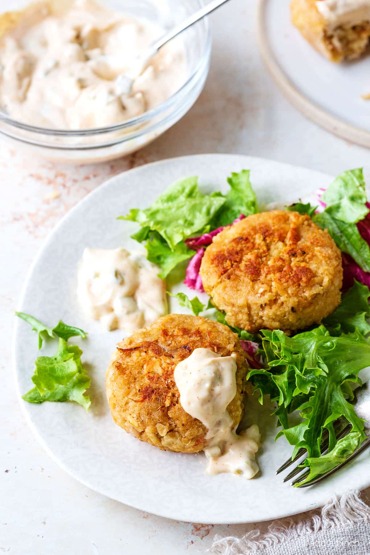 Plate with two crab cakes on a salad. 