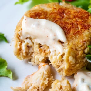 Lump crab meat shows in a golden brown crab cake on plate with salad.