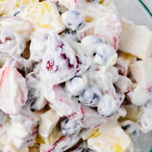 Fruit salad with a creamy dressing in a glass bowl.