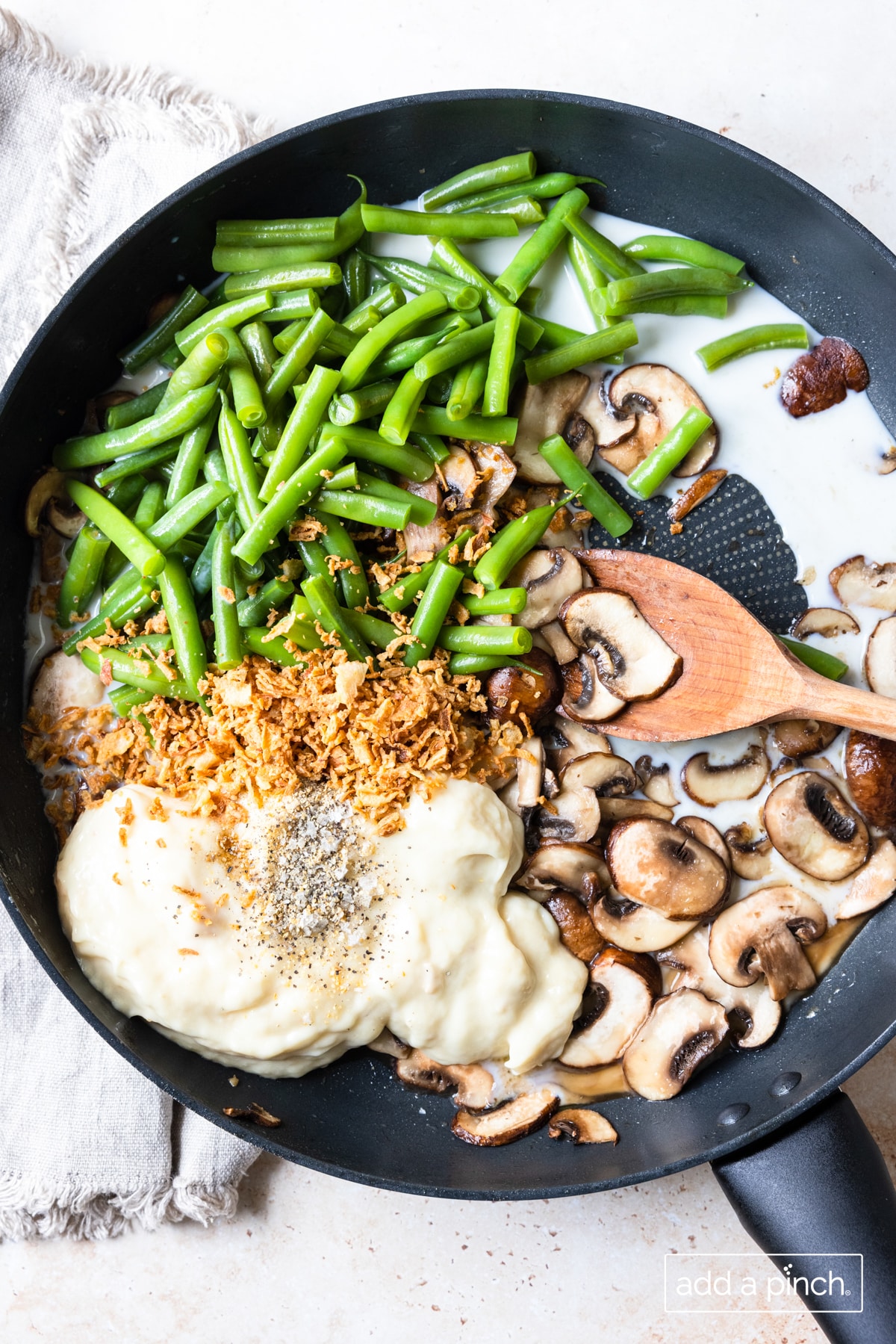 Ingredients for green bean casserole cooking in a skillet. 