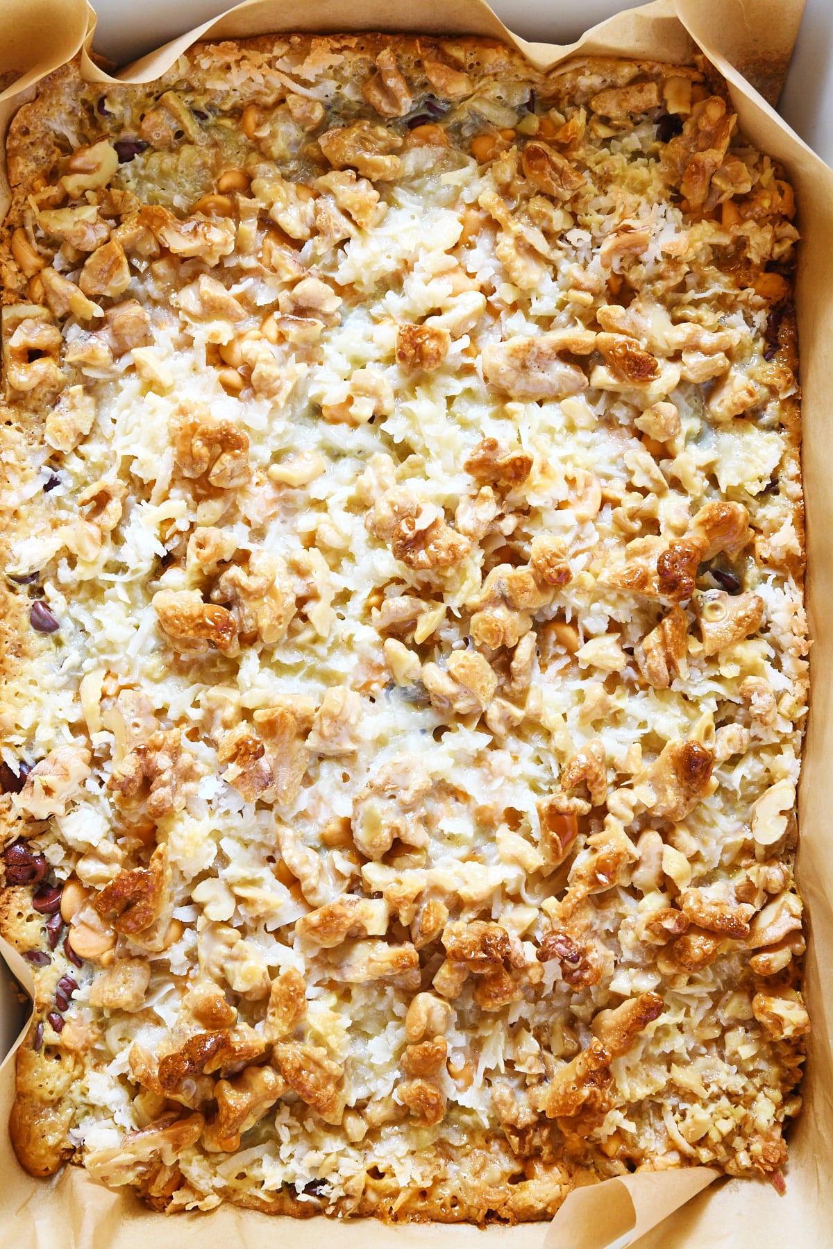 Baked cookie bars in a baking dish with parchment paper.