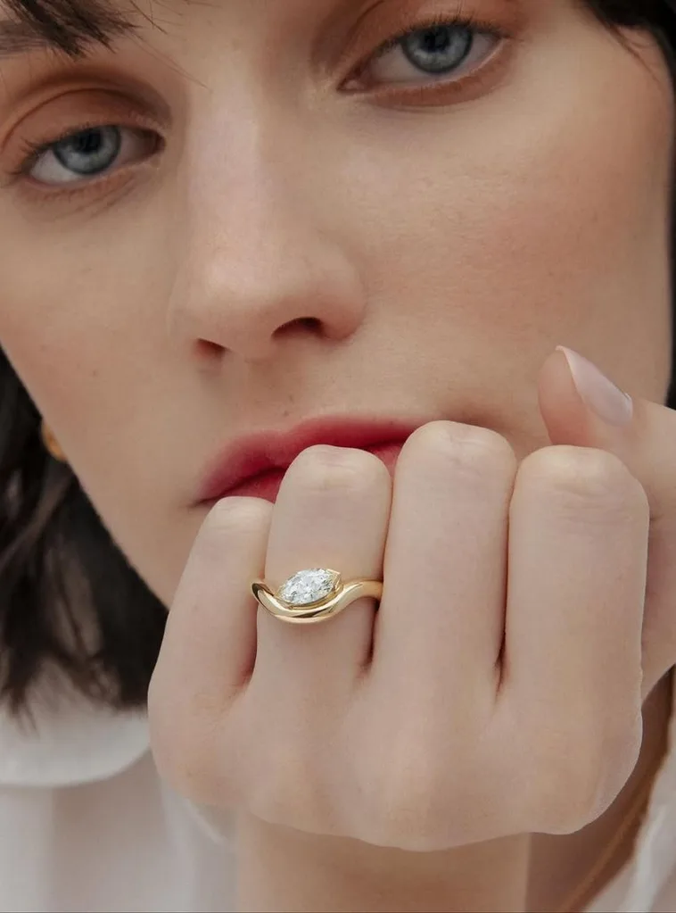 A model wearing a Cushla Whiting marquise cut diamond in a swirling gold band setting