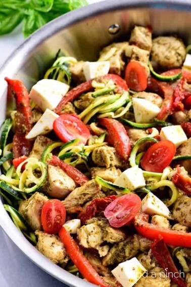 One Pan Pesto Chicken Recipe - This One Pan Pesto Chicken recipe makes a quick and easy answer to what's for supper? Made with chicken, pesto, peppers, tomatoes, zucchini and mozzarella, this will easily become a favorite! // addapinch.com