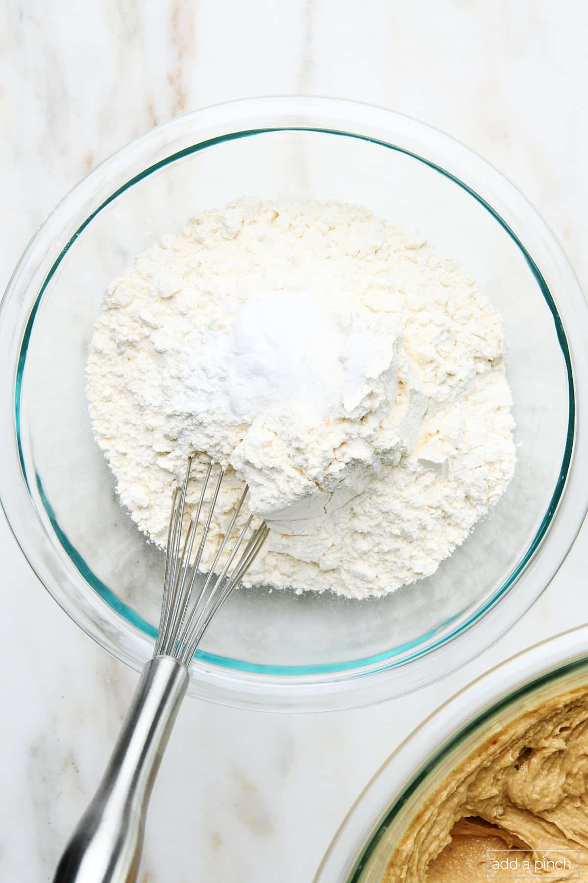 Baking powder and flour in a mixing bowl with whisk.