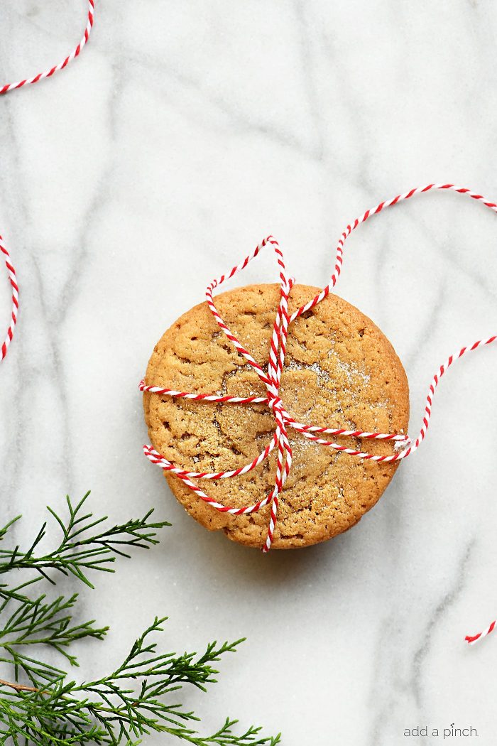 Stack of peanut butter cookies tied with red and white twine on a marble surface.