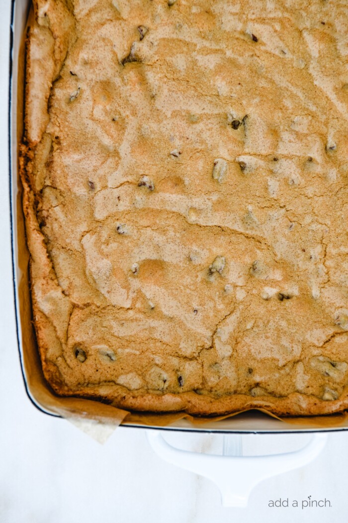 Pecan Chewies baked to a golden brown and cooling in baking dish on white marble counter.  // addapinch.com