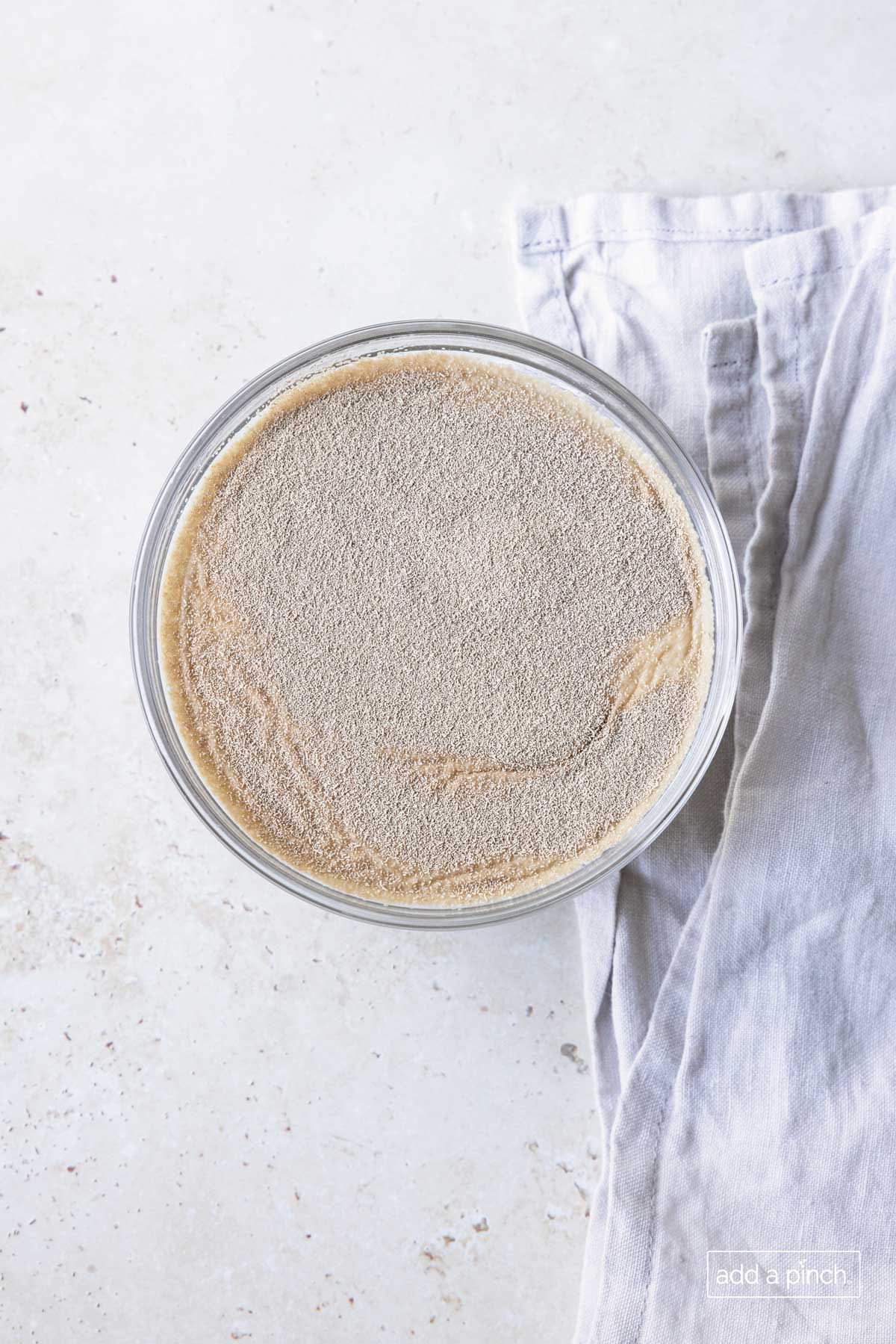 Photo of yeast sprinkled on water in a glass bowl.