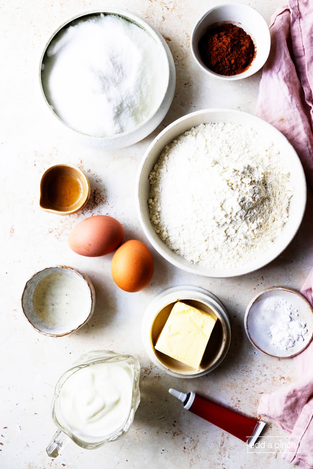 Flour, baking soda, butter, shortening, sugar, vanilla, eggs, buttermilk, red food coloring, and other ingredients ready to make red velvet cake.