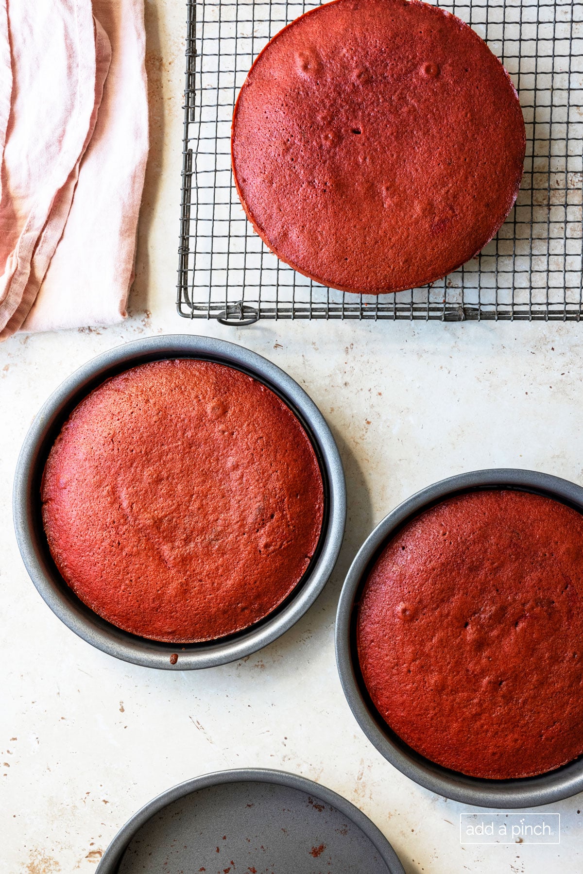 Photo of baked red velvet cake layers ready to cool on wire rack.