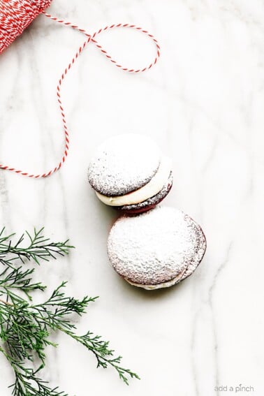 Red Velvet Cookies Recipe - These delicious cookies taste like your favorite red velvet cake in cookie form! Red Velvet cookies filled with cream cheese frosting and topped with a magical dusting of confectioner's sugar! // addapinch.com