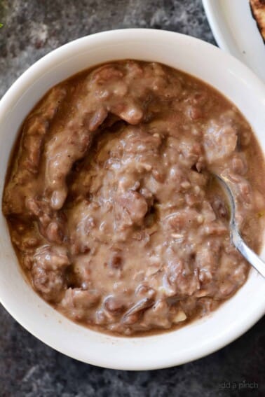 Refried Beans Recipe - This quick and easy refried beans recipe made with pinto beans, onion, and spices makes a delicious side dish for so many meals! // addapinch.com