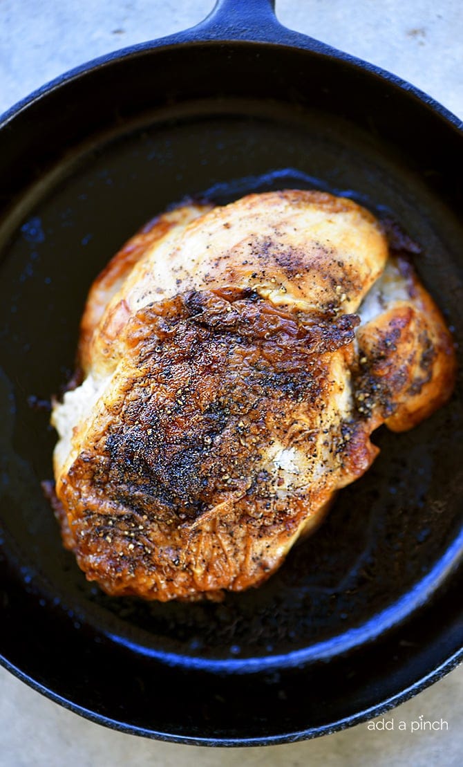 Photo of turkey with crispy skin in a cast iron skillet.