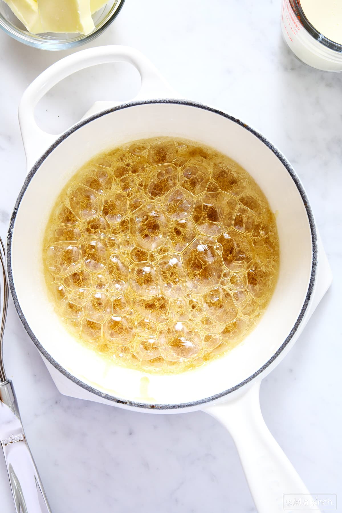 Bubbly caramel sauce being made in a white saucepan.