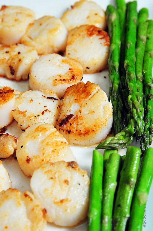 Seared scallops and asparagus on a white platter. // addapinch.com