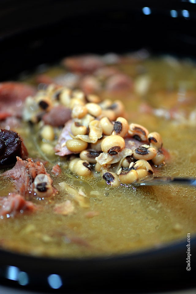 Black Eyed Peas cooking in pot lifted up with a spoon. 