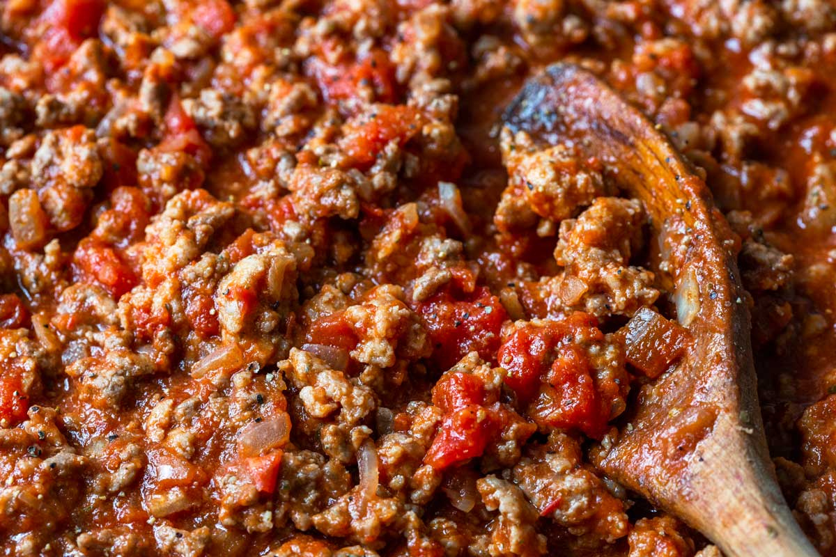 Horizontal photo of homemade spaghetti sauce with a wooden spoon.