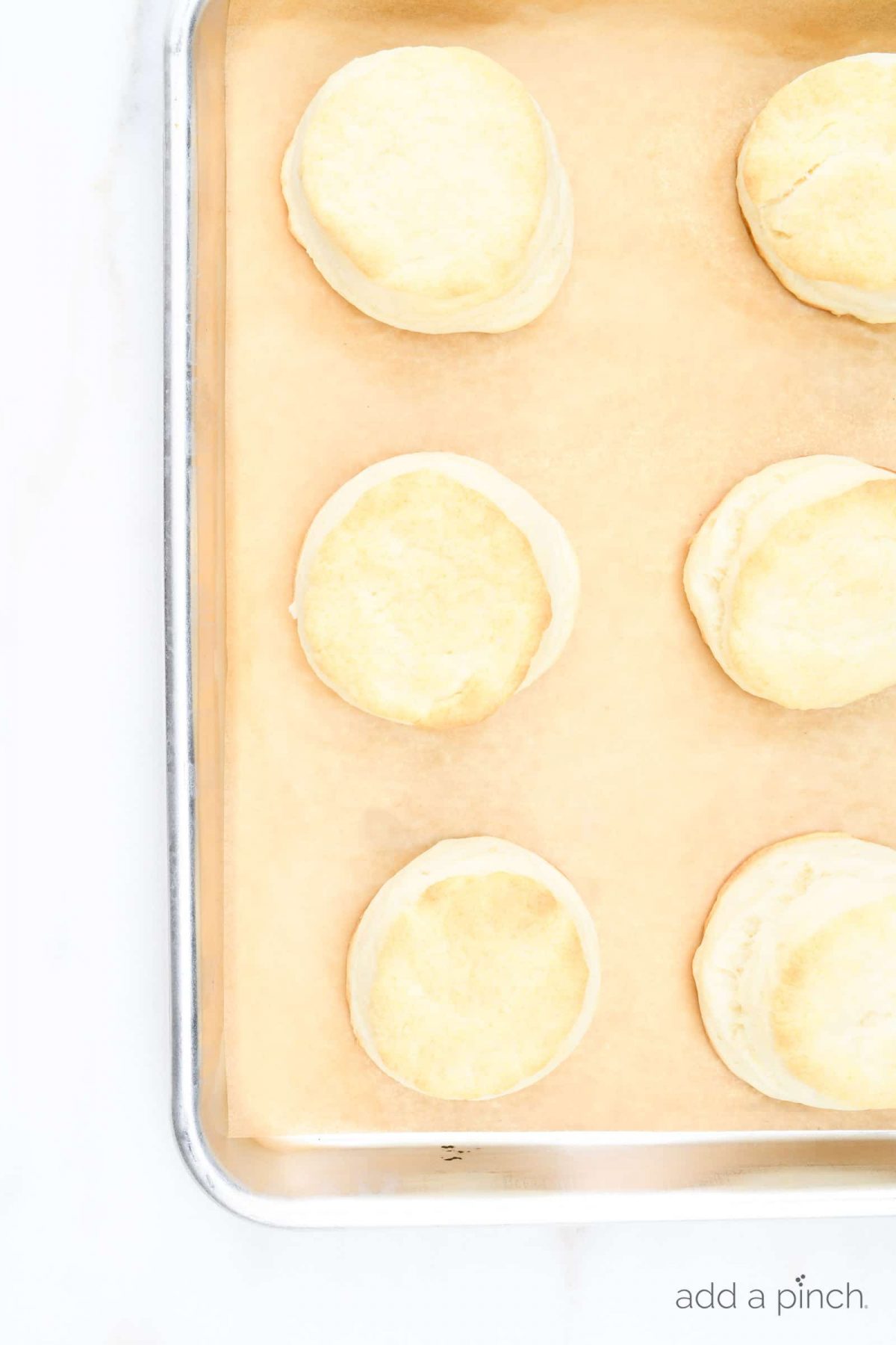 Photograph of biscuits on a baking sheet on a white background. // addapinch.com