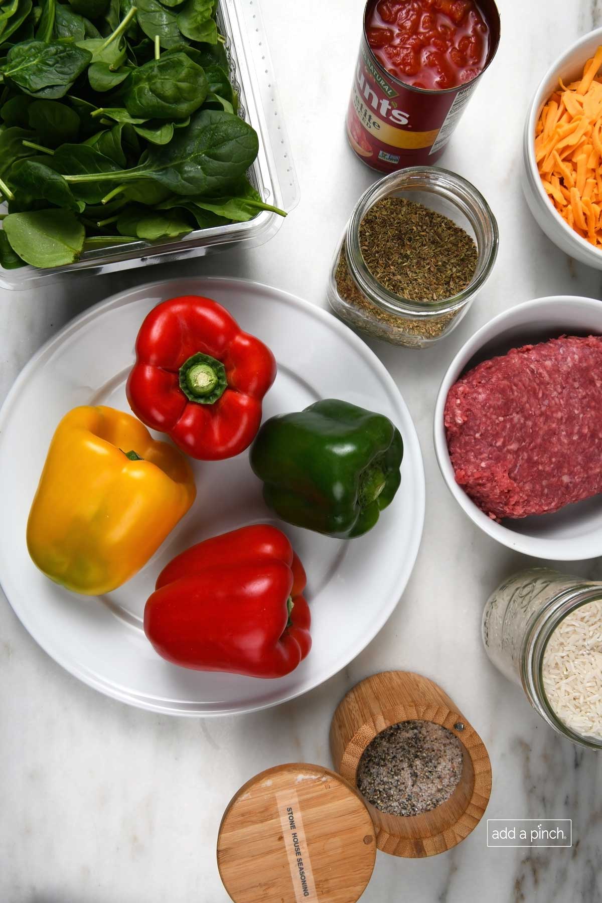 Spinach, tomatoes, shredded cheddar cheese, Italian seasoning, ground beef, rice, Stone House Seasoning, as well as red, green and yellow peppers ready to make stuffed peppers.